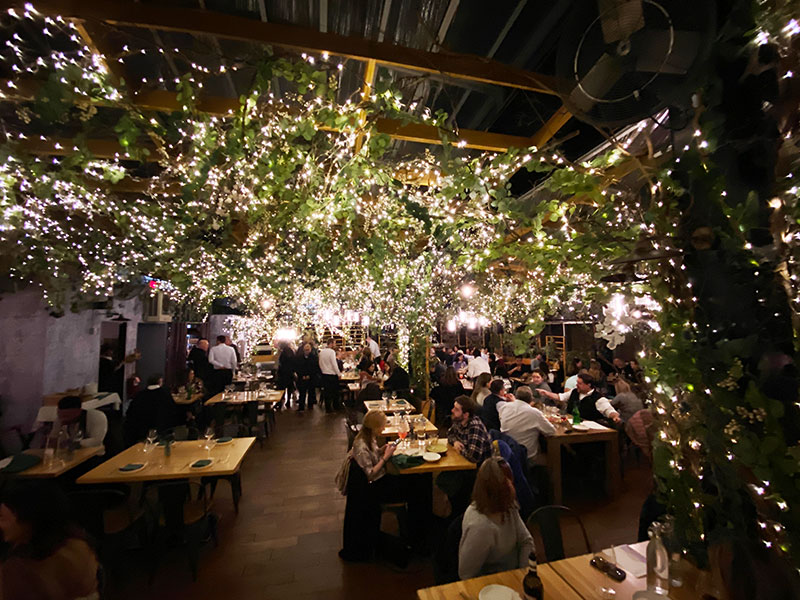 The interior of Serra at Eataly is decorated with lights and greenery. It can get cold in winter because technically its just a roof deck