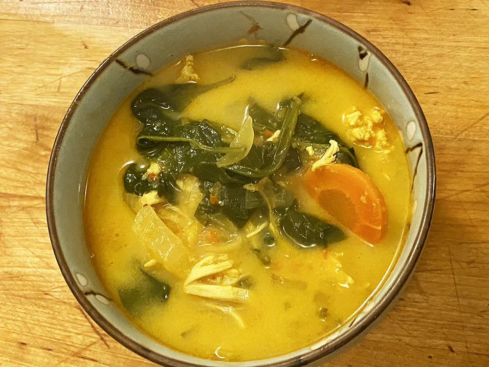 a bowl of curry chicken soup with spinach