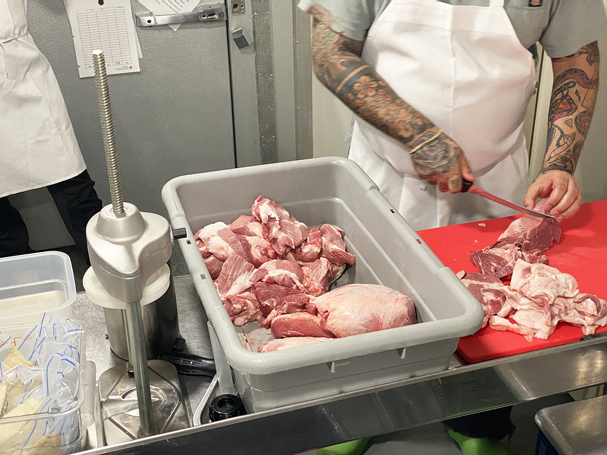 Cutting up chunks of pork at the Meat Hook to make sausage